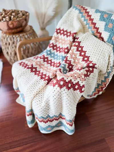 Gemstone Hues Crochet Blanket draped over a woven chair