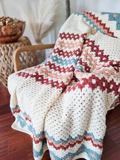 Close up of the Gemstone Hues Crochet Blanket's rust and blue diamond stripes