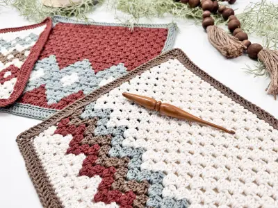 Gemstone Hues blanket panels in rust and cream with a crochet hook