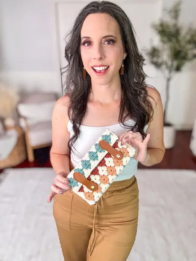 Woman holding a teal and cream Harvest Hues Crochet Clutch with leather tabs