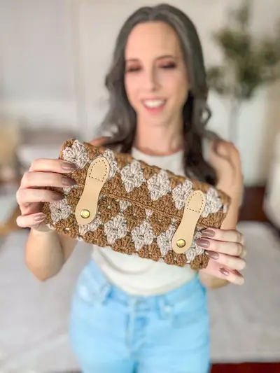 Woman holding a rust and cream Harvest Hues Crochet Clutch with tan leather tabs
