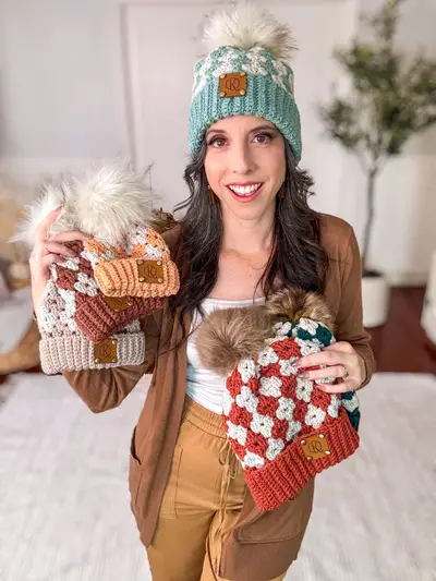 Woman holding Harvest Hues Crochet Beanies in rust and teal while wearing one