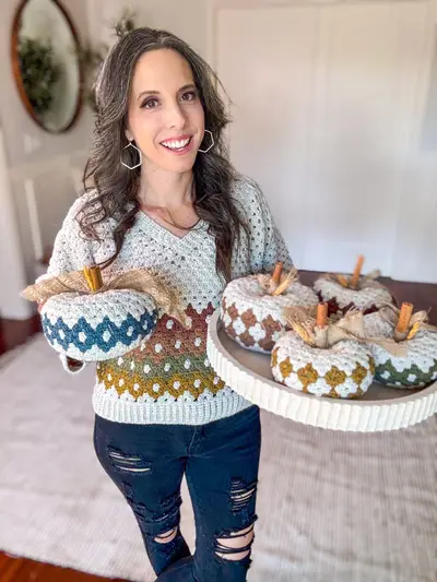 Woman holding a platter of Harvest Hues Crochet Pumpkins with cinnamon stick stems
