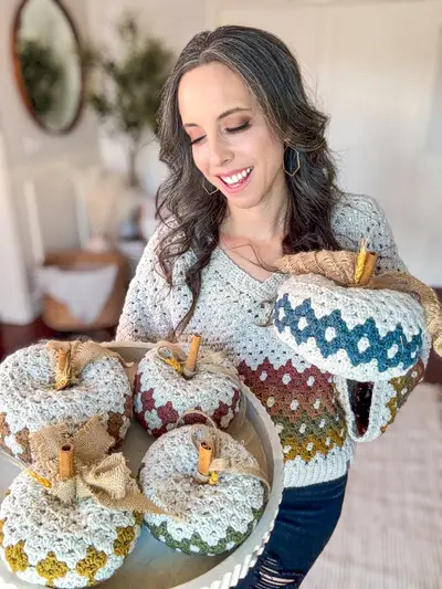 Smiling woman with Harvest Hues Crochet Pumpkins in mustard, rust and teal