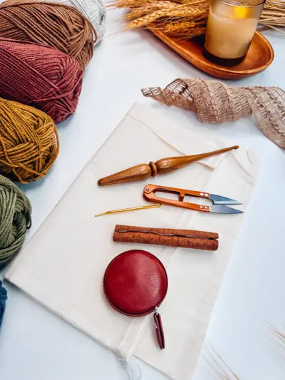 Supplies for Harvest Hues Crochet Pumpkins: yarn, cinnamon sticks, scissors and a crochet hook