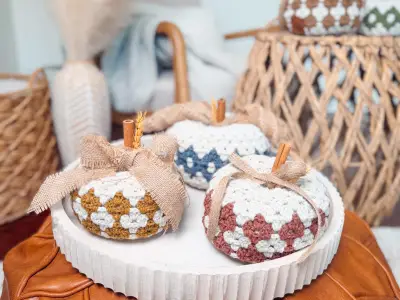 Three Harvest Hues Crochet Pumpkins with burlap bows on a wooden tray