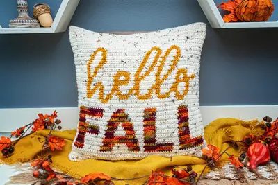 Hello Fall Crochet Pillow Cover on a mustard throw with orange fall leaves