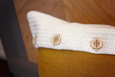 Close up of the cream crochet flap with wooden leaf buttons on mustard burlap