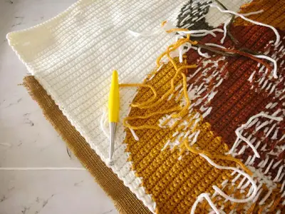 Wrong side of the Hello Pumpkin colorwork with yarn tails and a yellow hook