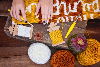 Hands crocheting the Hello Pumpkin Pillow with cream, rust and mustard yarn cakes