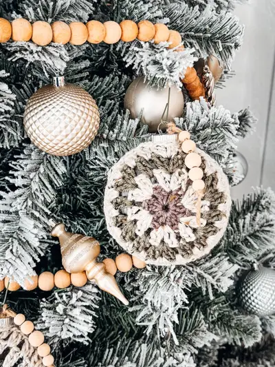 Hexagon Granny Bauble Ornament in cream and taupe hanging on a flocked Christmas tree