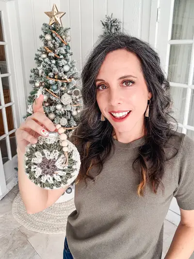 Woman holding up a Hexagon Granny Bauble Ornament by a Christmas tree
