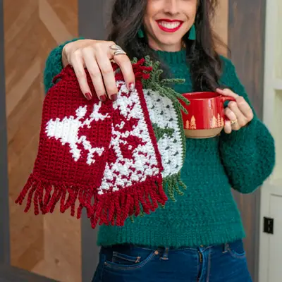 Woman holding a red Holiday Crochet Mug Rug with a reindeer design and a red mug