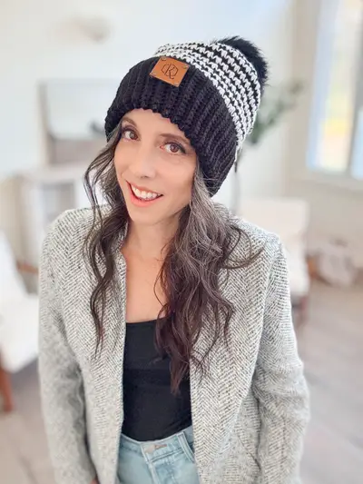 Woman wearing a black and white Houndstooth Crochet Beanie with a pom pom