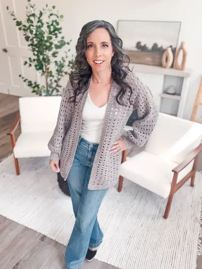 Woman wearing the gray Hummingbird Cardi, an open mesh cardigan, with jeans