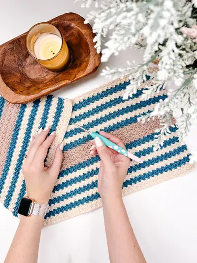 Hands crocheting the Just a Rectangle bag panel in teal, tan and cream stripes