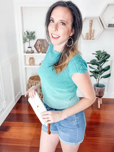 Woman wearing the teal short sleeve Lovely Lace Crochet Sweater with denim shorts
