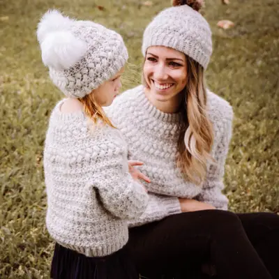 Mom and daughter in matching oatmeal Macchiato Crochet Beanies and sweaters outdoors