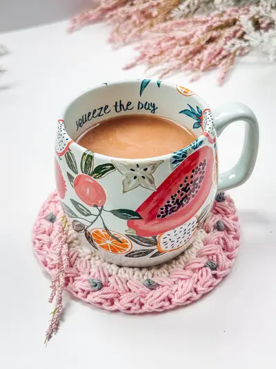 Floral coffee mug sitting on a pink Macchiato Crochet Coaster