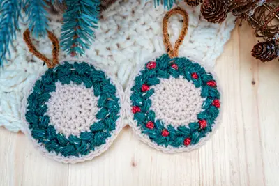 Two teal and cream Macchiato wreath ornaments with red bobbles
