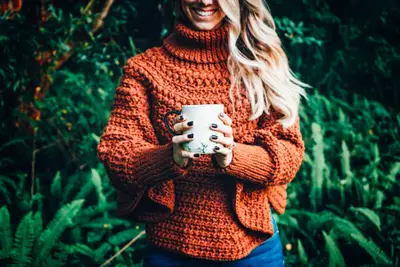 Rust Macchiato Crochet Poncho worn outdoors with a cup of coffee