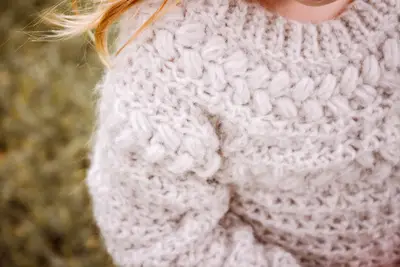 Close up of the textured yoke on the oatmeal child Macchiato Crochet Sweater