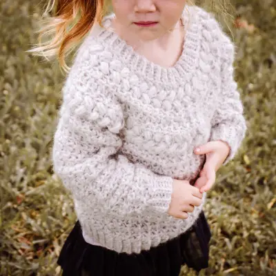 Little girl wearing the oatmeal Macchiato Crochet Sweater in child sizes