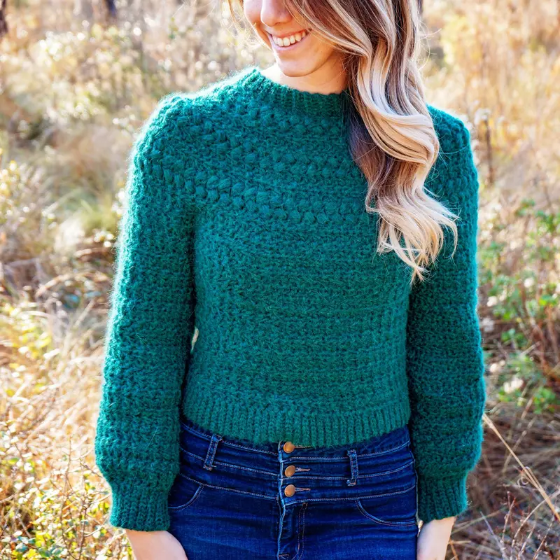 Woman wearing the green Macchiato Crochet Sweater with high waisted jeans