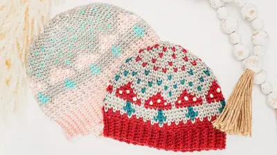Pink and red Mushroom Crochet Beanies laid flat with a tassel