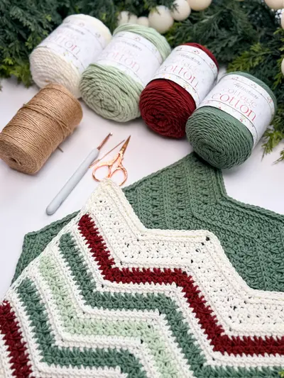 Petal Loop Chevron Washcloth in cream, sage and red with skeins of cotton yarn