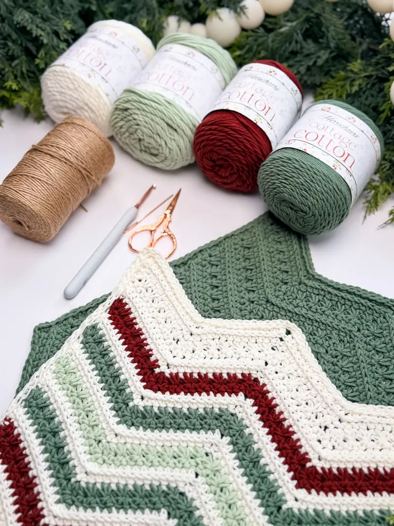 Petal Loop Chevron Washcloth in cream, sage and red with skeins of cotton yarn