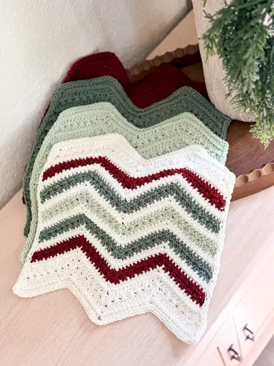 Stack of Petal Loop Chevron Washcloths in red, green and cream zigzag stripes