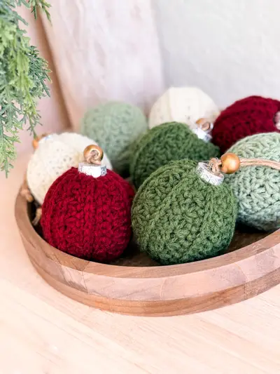 Bowl of Petal Loop Stitch Ornaments in red, sage, green and cream