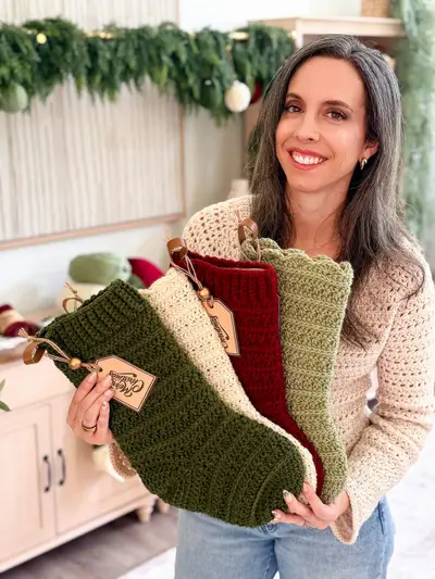 Smiling woman holding Petal Loop Stitch Stockings with personalized tags