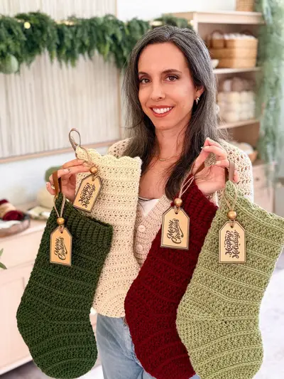 Woman holding up four Petal Loop Stitch Stockings with tags