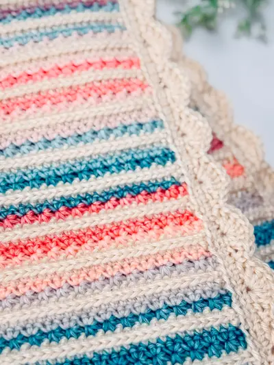 Close up of the scalloped cream border on the Petal Loop Stitch Striped Blanket