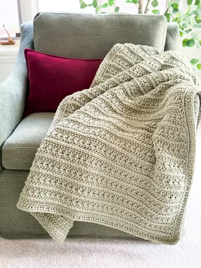 Sage Petal Loop Stitch Textured Blanket draped over a green sofa