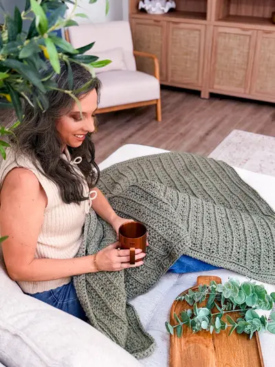Woman with a coffee mug under the sage Petal Loop Stitch Textured Blanket