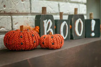 Two orange crochet pumpkins with black beads beside BOO blocks on a mantel