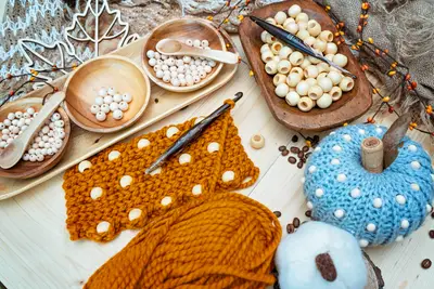 Mustard beaded crochet swatch with wood beads, yarn and a light blue pumpkin
