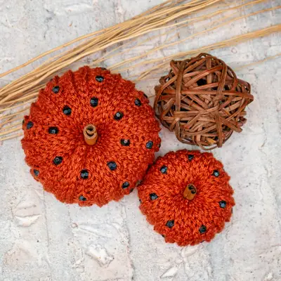 Top view of two orange crochet pumpkins with black beads and a wicker ball