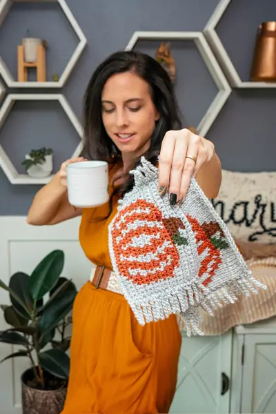 Woman holding a white mug and two fringed Pumpkin Coffee Mug Rugs