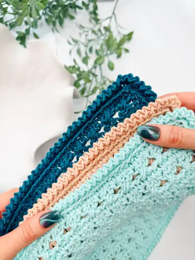 Hands holding peach and teal Reed Washcloths