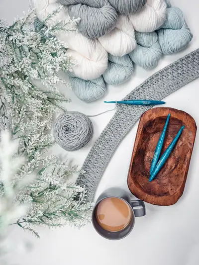 Robin Duster in progress with gray and blue yarn, crochet hooks and coffee