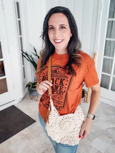 Woman wearing a cream Seven Hexi Granny Bag crossbody with an orange tee