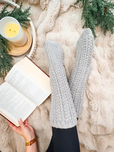 Gray Snowdrift Wheat Slipper Socks on a faux fur rug with an open book