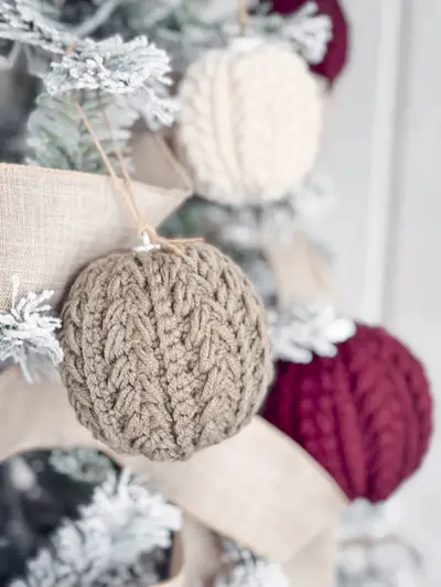 Snowy Wheat Ornament in taupe hanging on a flocked tree with red and cream ornaments
