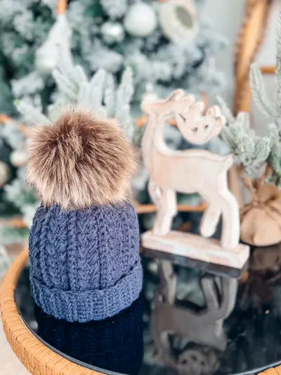 Blue Snowy Wheat Stitch Crochet Hat with a faux fur pom pom by a wooden reindeer