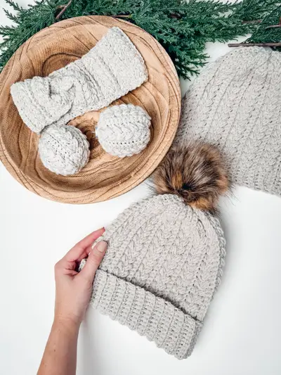 Gray Snowy Wheat Stitch hat and ear warmer with pom poms in a basket