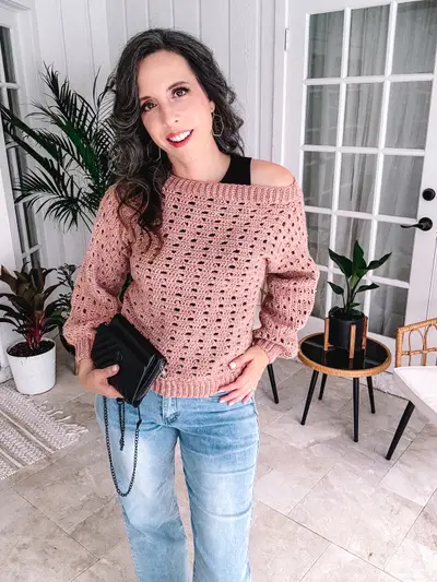 Woman in the off the shoulder pink Sparrow Sweater with a crossbody bag